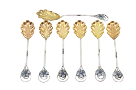  Conjunto de seis colheres de chá e pá de açúcar em prata dourada na concha em forma de flores.